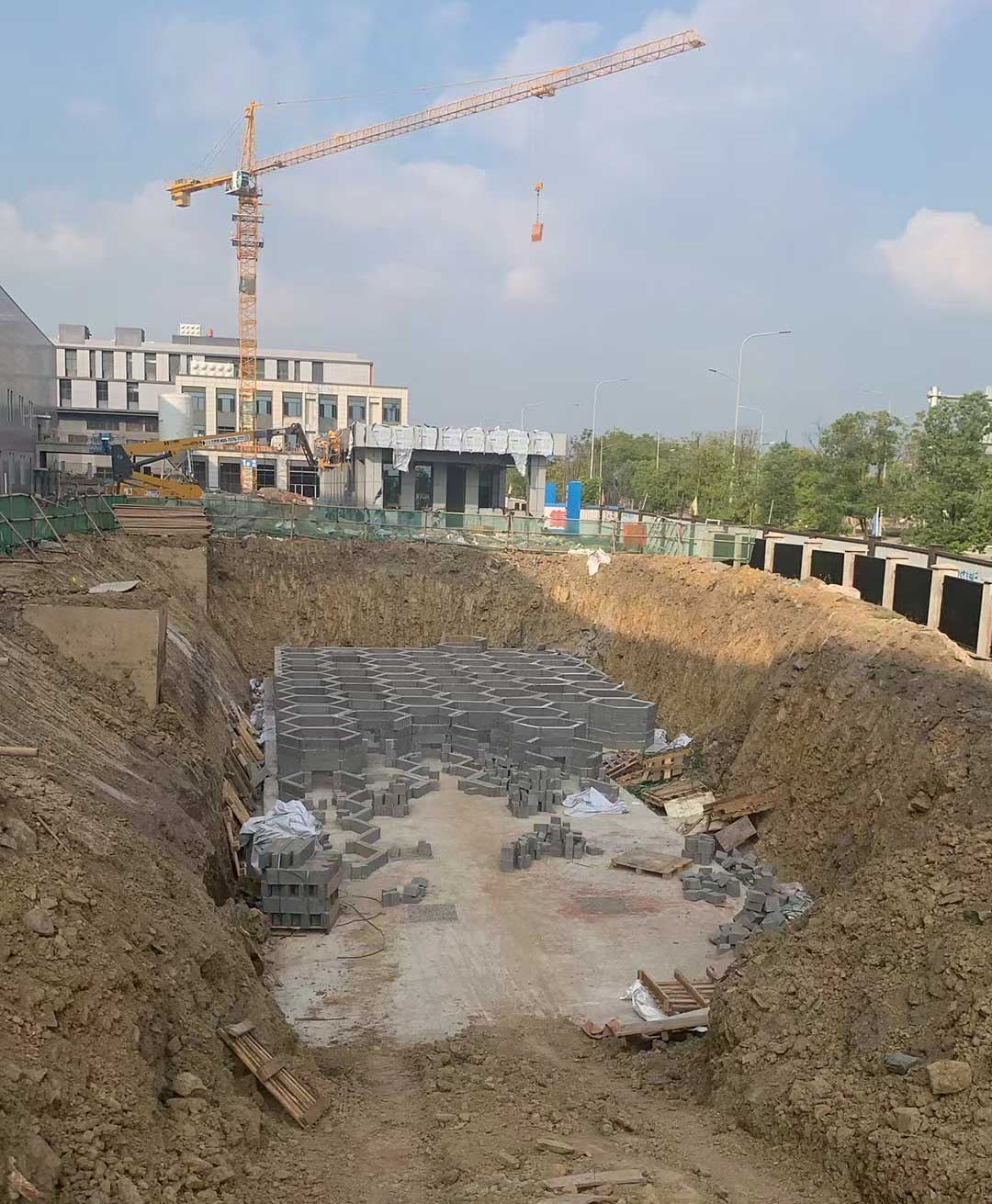 硅砂雨水收集池施工现场，深基坑内正在拼装灰色蜂巢状蓄水模块