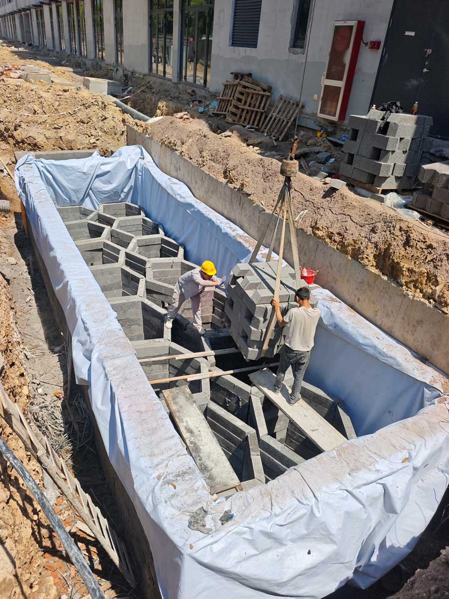 狭小地形硅砂雨水收集池施工现场，工人正在基坑内吊装六边形模块