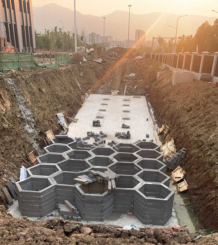 海绵城市雨水调蓄设施主体拼装现场，夕阳下深基坑内密集的硅砂蜂巢结构