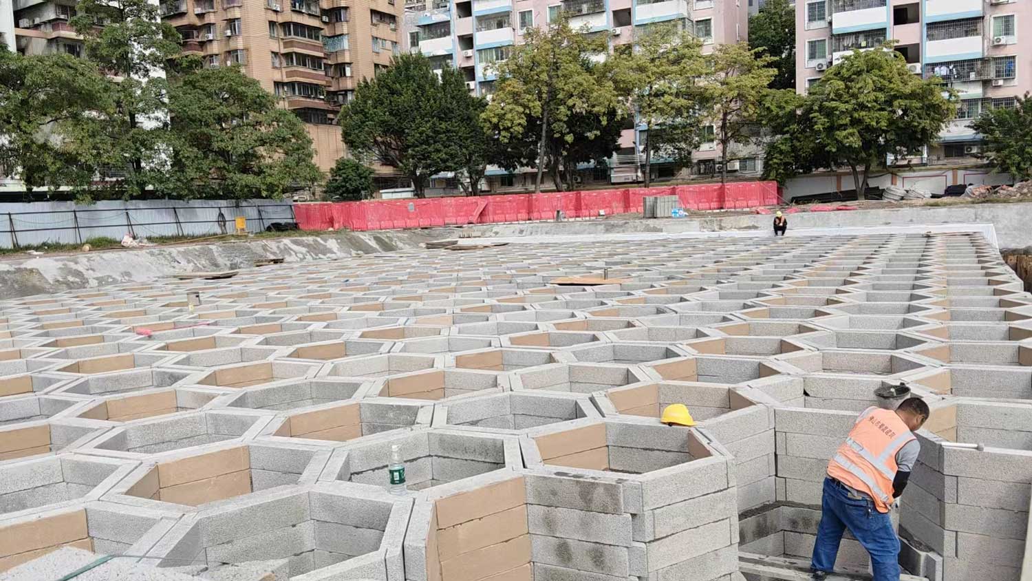 硅砂模块雨水收集池安装作业，施工人员在基坑内拼装蜂窝状蓄水模块实景