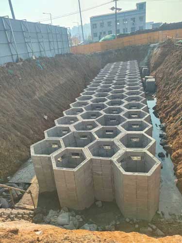 建筑工地深基坑内呈现出多层重叠、整齐划一的正六边形蜂巢状硅砂雨水收集池