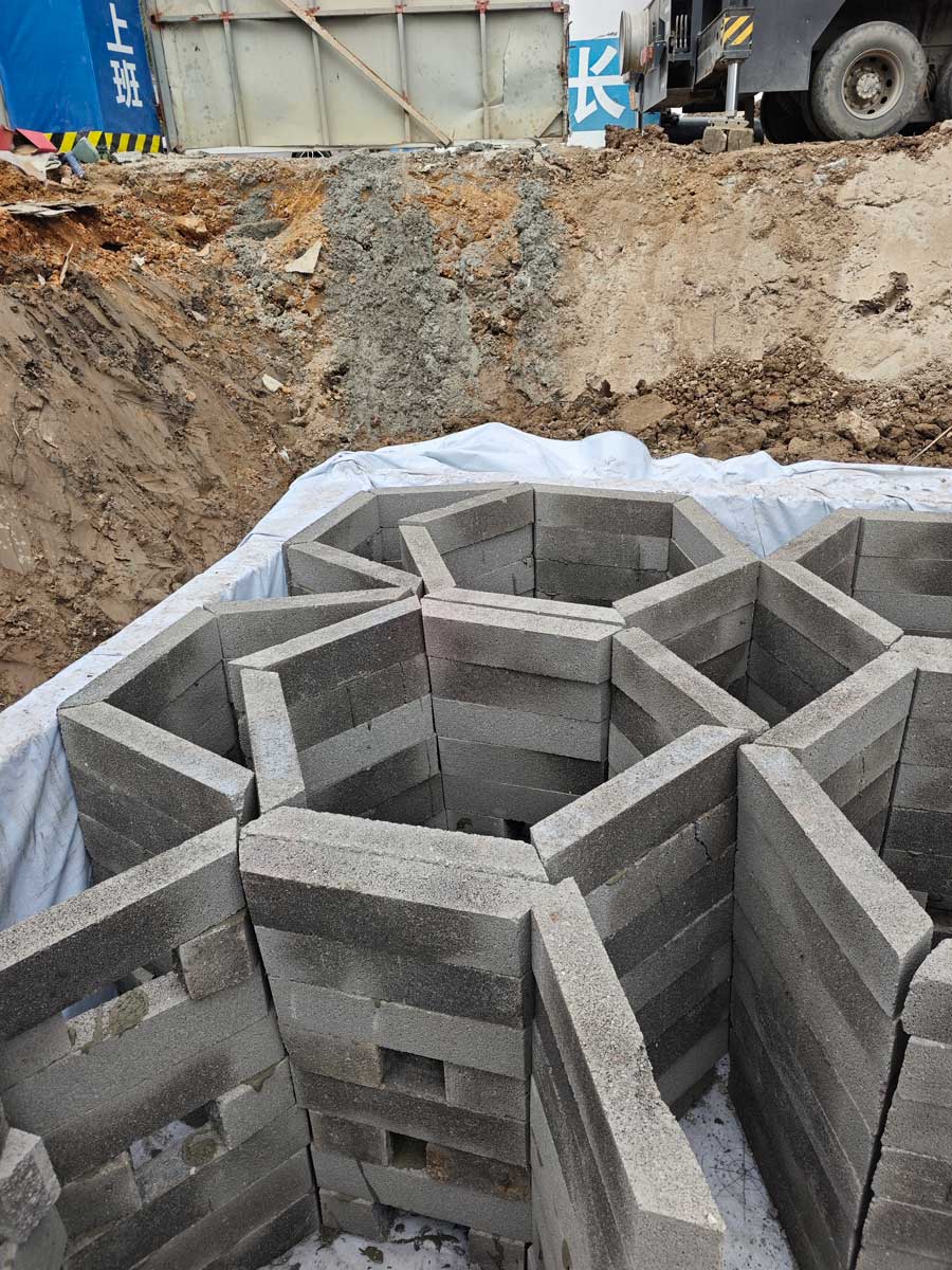 施工中的硅砂雨水收集池,呈现出标志性的正六边形蜂巢状中空型格,周围铺有白色的防水土工布 施工中的硅砂雨水收集池,呈现出标志性的正六边形蜂巢状中空型格,周围铺有白色的防水土工布