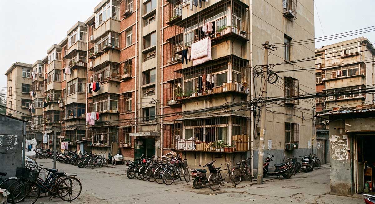 典型90年代老旧小区狭窄街景,展示海绵化改造前地面空间紧张与铺装硬化的现状 典型90年代老旧小区狭窄街景,展示海绵化改造前地面空间紧张与铺装硬化的现状