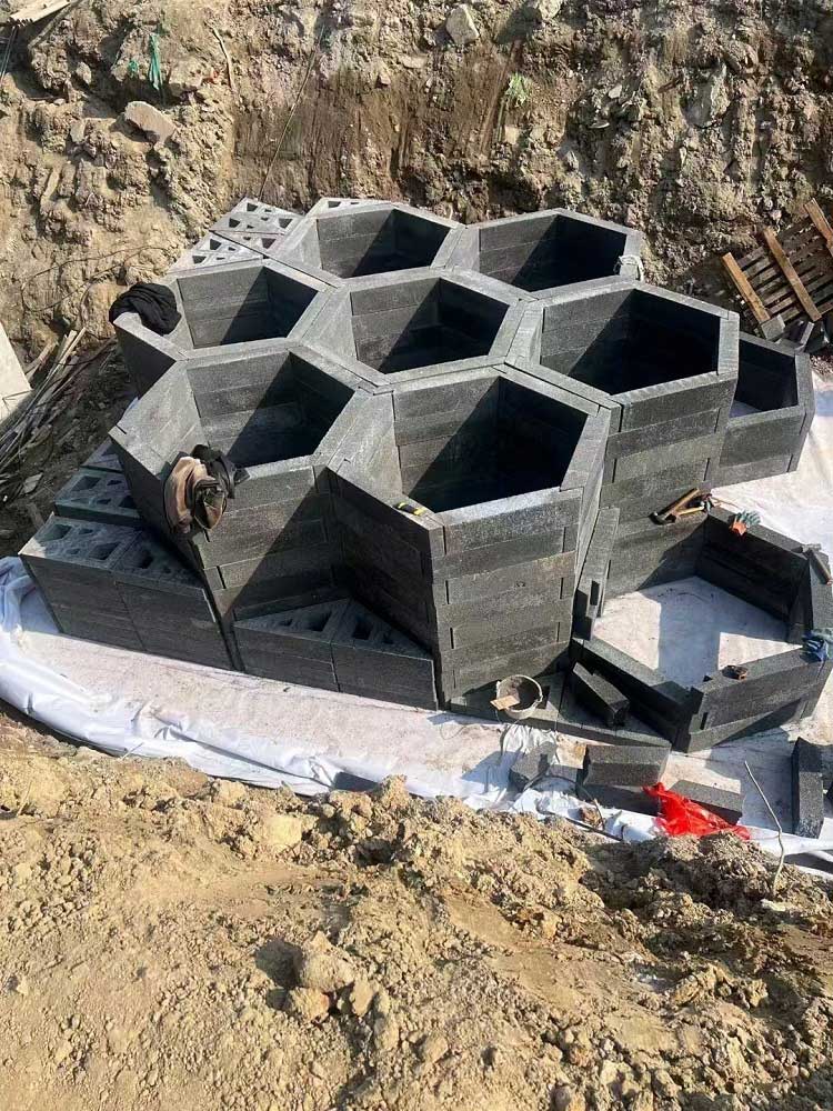 基坑内由深灰色硅砂模块与三角形补角砌块拼装而成的中空蜂巢状雨水蓄水模块局部细节 基坑内由深灰色硅砂模块与三角形补角砌块拼装而成的中空蜂巢状雨水蓄水模块局部细节